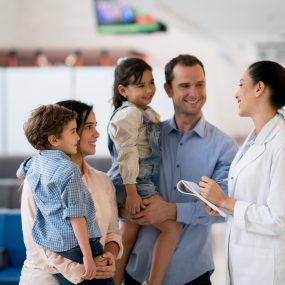 Doctor talking to a happy Latin American family at the hospital - healthcare and medicine concepts